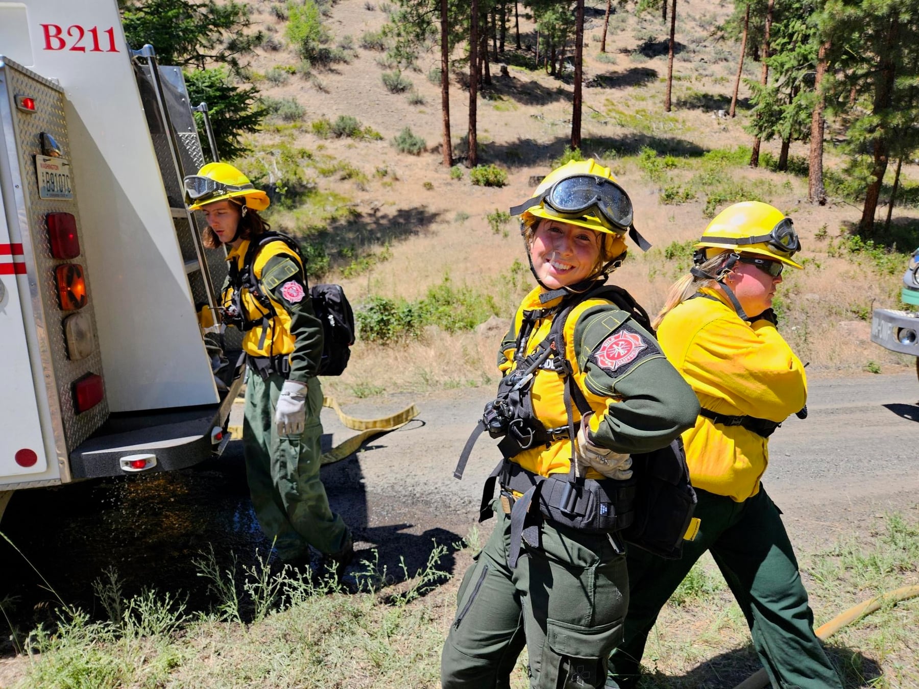 Wildland firefighters smile together beside an apparatus during field operations