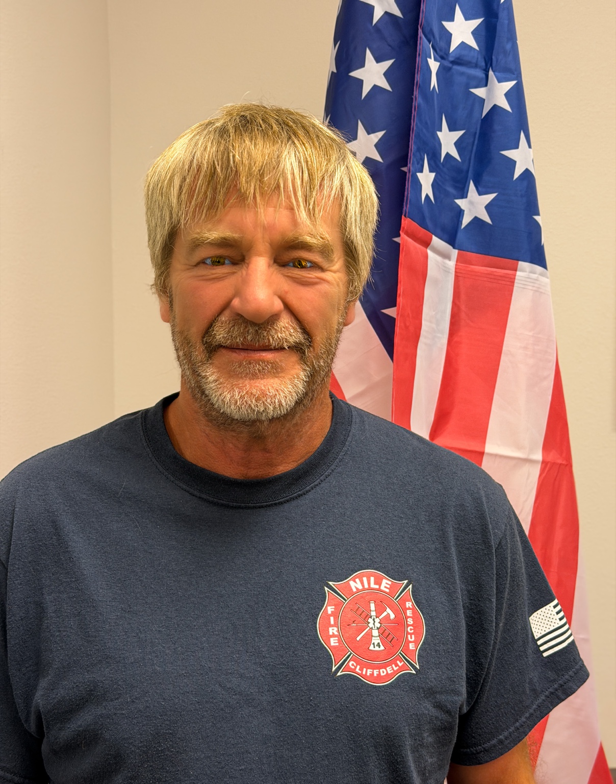 Commissioner Mike Van Amburg, Vice Chair, wearing a Nile-Cliffdell Fire and Rescue shirt in front of an American flag