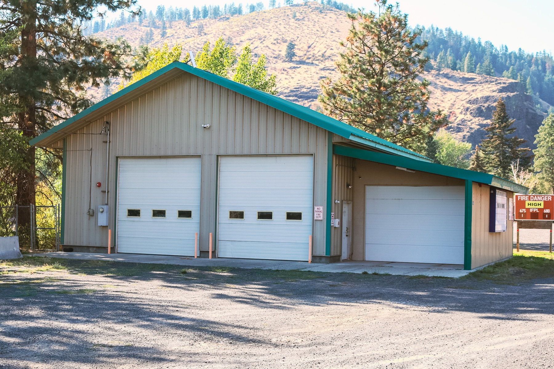 Station 10 exterior with its three apparatus-bay doors and the SR 410 hillside behind it